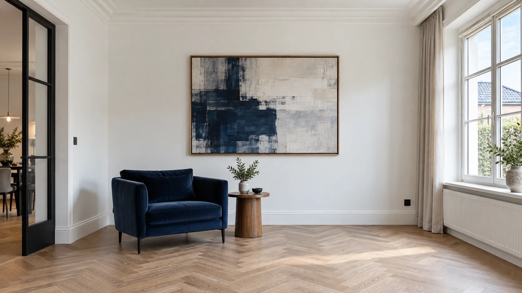 Lichte woonkamer met witte muren, eikenhouten visgraatvloer en een donkerblauwe fauteuil